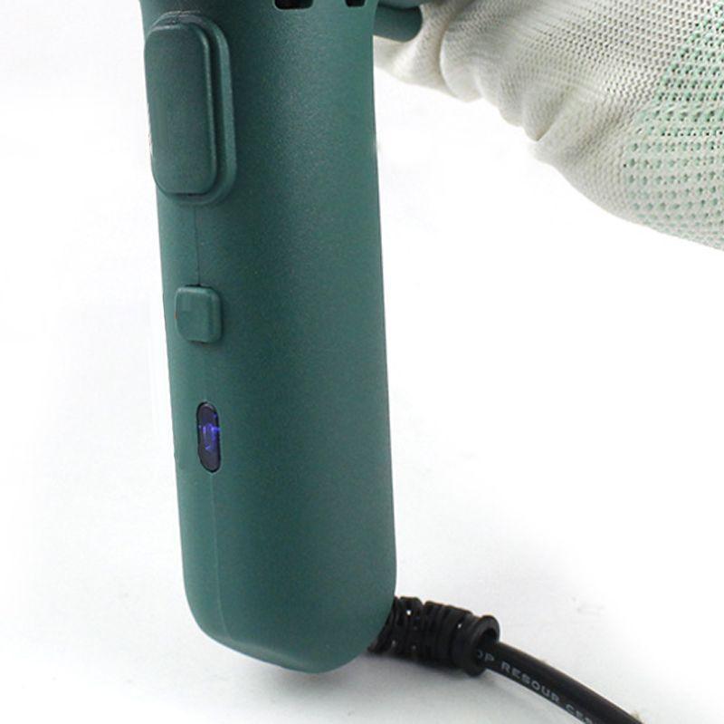 Close-up of a green cordless power tool handle with control buttons and charging cable